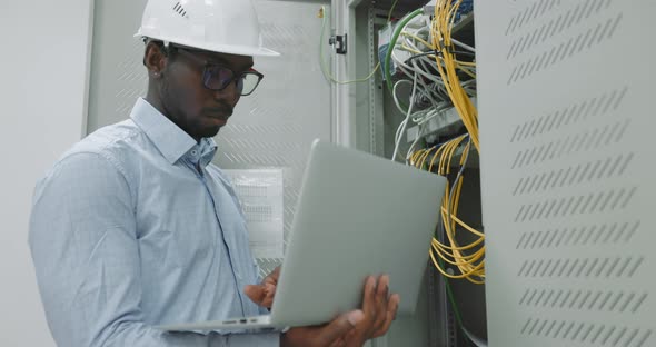 Man Using a Laptop While Working in a Server Room