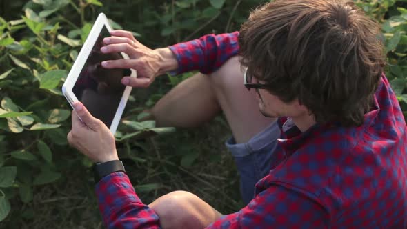 A young and promising farmer checks the soybean crop in the field with a tablet