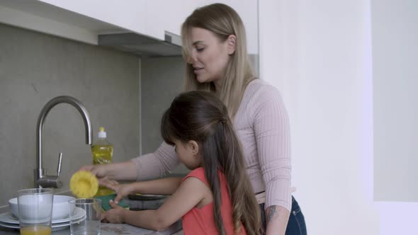 Cheerful Mom Teaching Girl To Wash Dish