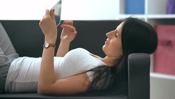 Happy Young Woman with Tablet Pc Laying on Sofa