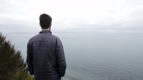 Man stoically gazes out into the Pacific Ocean.