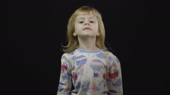 Little Baby Girl in Pajama Is Fooling Around and Make Faces, Black Background