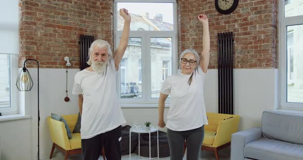 Mature Couple in Sports Uniforms Standing in the Middle of Living-Room