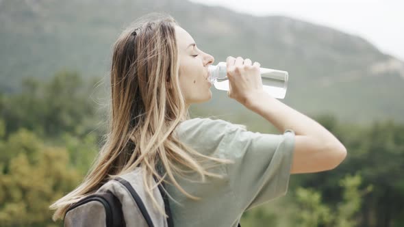 A Woman Drinks Water From a Bottle During Hiking