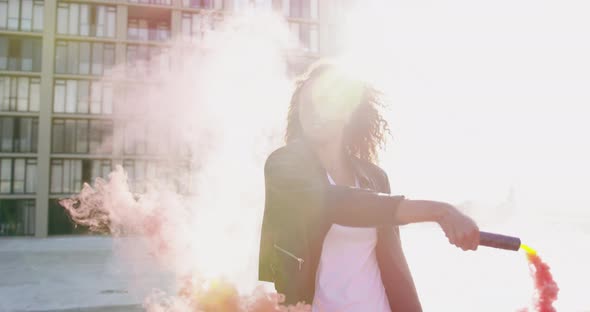 Fashionable young woman on urban rooftop using a smoke grenade