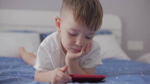 Cute Little Boy Preschool Child Using a Phone or Digital Tablet Technology Device Looks Telephone