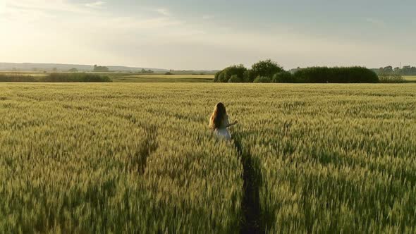 Girl Walking in Field at Sunset Flying Around