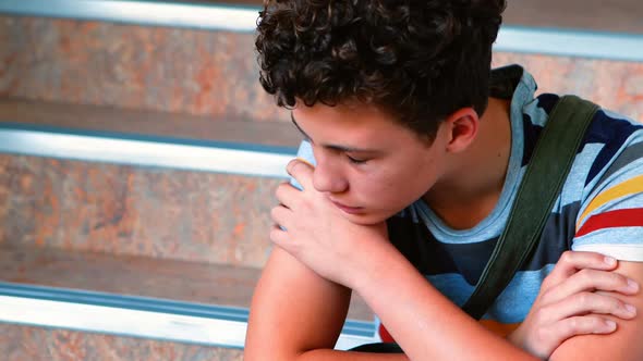 Sad schoolboy sitting alone on staircase