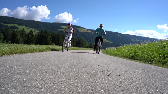 Couple Woman and Man on Electric Eco Bike Cycling Italy Dolomites Alps
