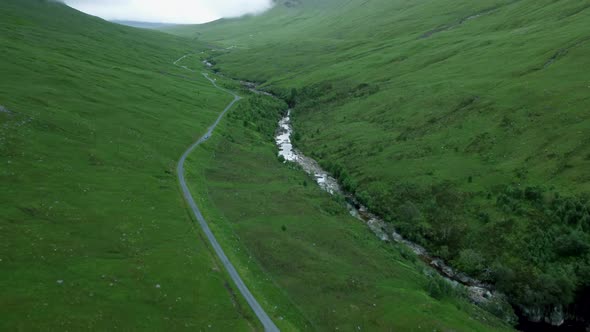 Pan up drone shot reveals country road in Scottish Highlands