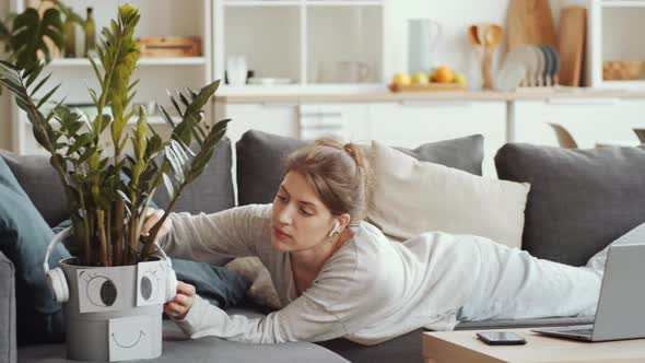 Cheerful Woman Sitting on Couch and Web Calling on Smartphone at Home