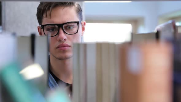 College Library. Male Student Searching For Book On Bookshelves