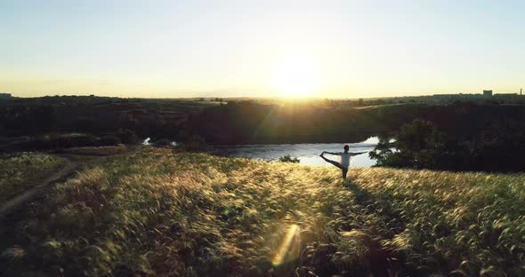 Girl doing yoga on a beautiful meadow at sunset. Slow motion.