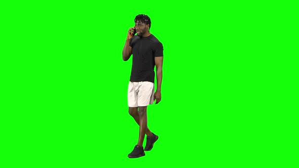 African American Man Walking and Talking on the Mobile Phone at Green Screen, Chroma Key.