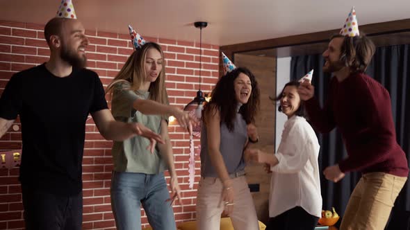 Joyful Friends in Hats Dancing on Birthday Party Celebrating Holiday at Home Slowmo