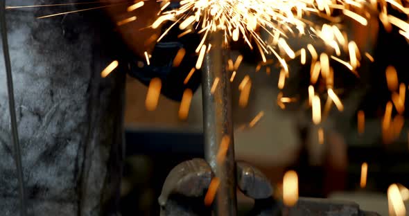 Blacksmith using grinder machine on rod 