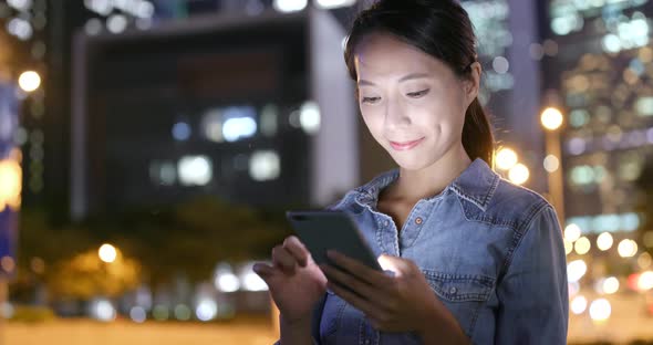 Woman use of smart phone in city at night 