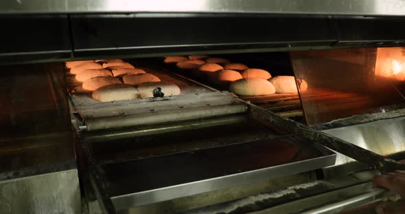 A Baker Manually Pulling The Deck Oven Loader, Moving The Raw Bread Dough Into The Oven - Bread Maki