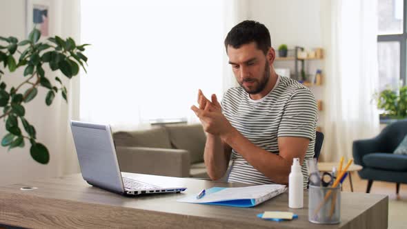 Man Using Hand Sanitizer at Home Office