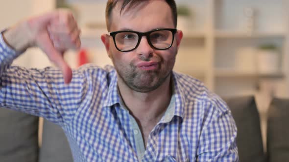 Close Up of Disappointed Young Man Showing Thumbs Down 