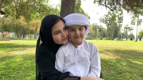 Emirati Mother in Abaya with son. Arab woman together with her young boy child on Kandora dish dash.