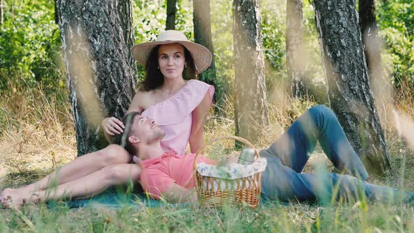 Picnic Time. Happy Young Couple Sitting and Smiling Outdoors. Man Laying on Her Hands. Outdoors in