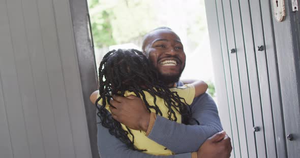 Happy african american daughter and father hugging in doors