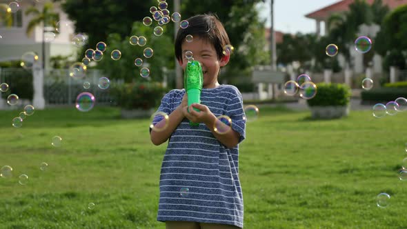 Cute Asian Child Shooting Bubbles From Bubble Gun In The Park