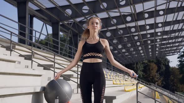 Young Woman in Fitness Clothes Doing Phisical Exercises with Jump Rope During Sport Training