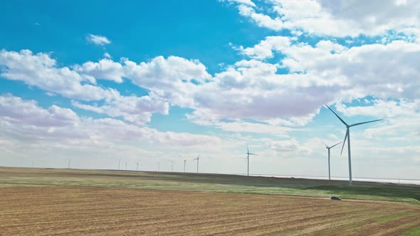 Car Moving By Rustic Road on Wind Electric Generators Background