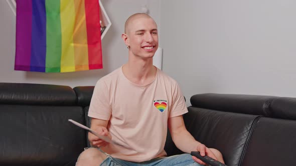 French Caucasian Bald LGBTQAI Activist Waving French Flag While Sitting in His Apartment on Black