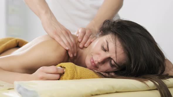 Male Masseur Doing Massage for Attractive Young Woman. Female with Closed Eyes