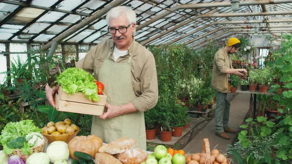 Elderly Farmer Posing in Greenhouse with Fresh Produce