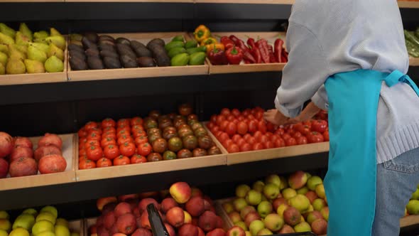 Female Worker Placing Tomatoes on Store Shelf