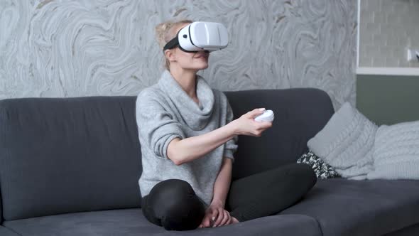 Young Woman Watching Videos or Playing with VR Glasses on Head