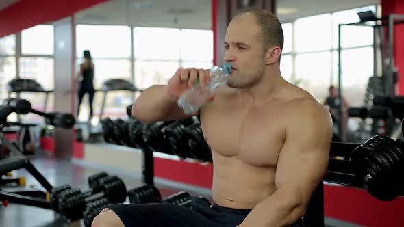 Muscular man drinking fresh water after active workout in gym, healthy lifestyle