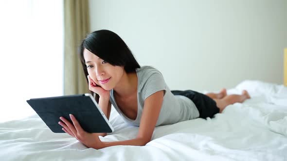 Woman using digital tablet computer and and sitting on bed