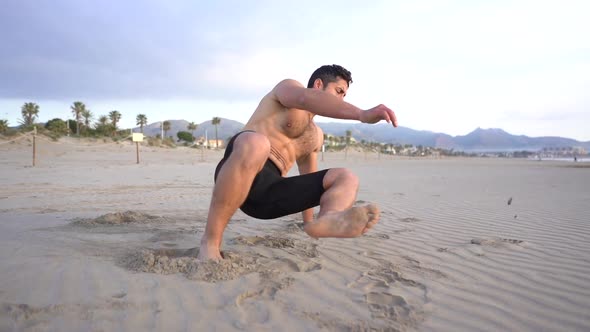 Man doing functional floor exercises in the sand on the beach