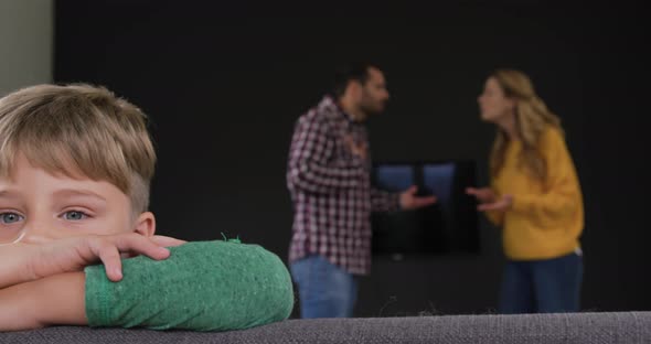 Boy leaning on sofa while parents arguing in background at home 4k