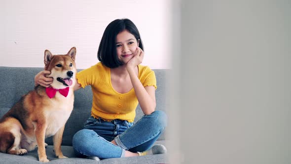 Young woman watching TV on sofa with her dog.