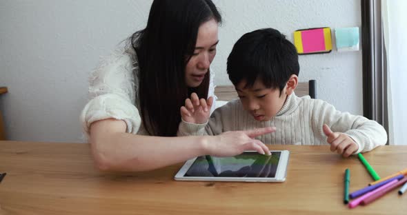 Asian mother at home using tablet with her child for homeworks