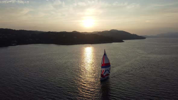 Sailboat passing slowly through calming sunset on her way to open seas - Norway summer through leroy