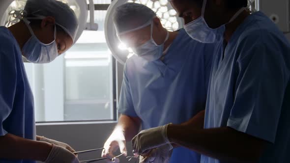 Multi-ethnic group of male and female surgeons working together in a hospital operating theatre, wea