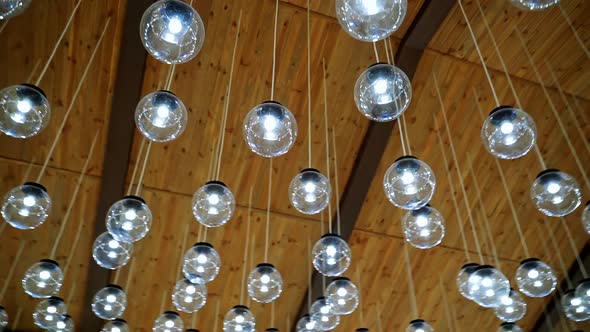 Crystal balls hanging from brown ceiling. Beautiful ceiling with round glass light bulbs. Motion cam