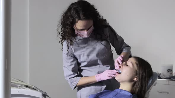 The orthodontist using dental impression tray on woman teeth.