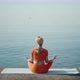 A Woman Sits in a Lotus Position Alone on the Seashore - VideoHive Item for Sale
