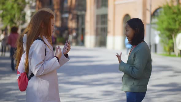 Side View of Redhead Schoolgirl Filming Video on Phone of Asian Classmate Dancing