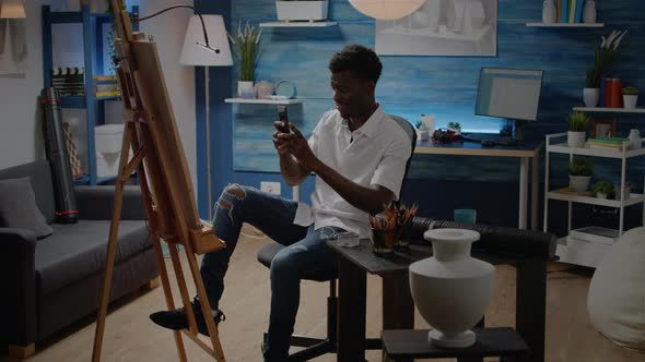 Black Young Artist with Smartphone Seeking Inspiration