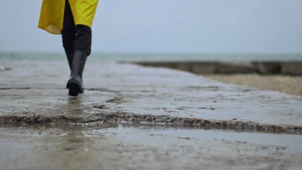 Person Walking Toward Pier Rain Boots Steps in Puddle Closeup