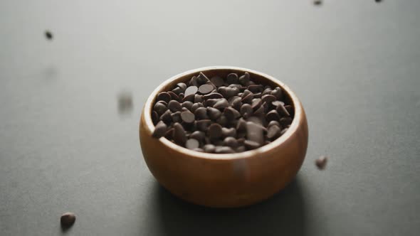 Video of wooden bowl of chocolate chip over grey background